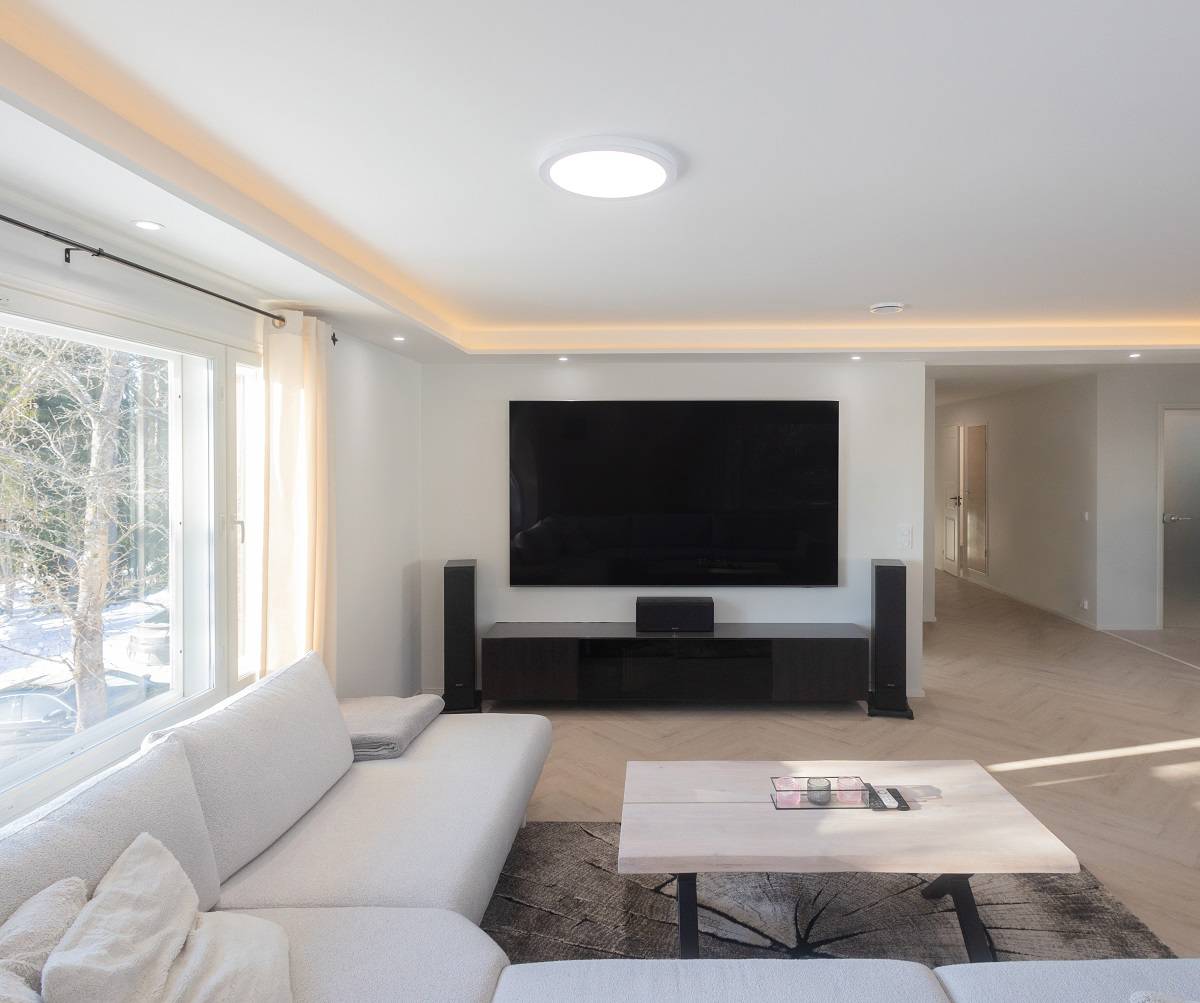 Soggiorno con soffitto parzialmente ribassato con striscia led, spot led e una plafoniera al centro.